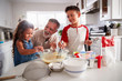 © Monkey Business - Brother and sister standing at the kitchen table making cake mix with their grandfather, close up
