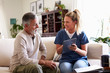 © Monkey Business - Female healthcare worker sitting with a senior Hispanic man in his living room during a home visit