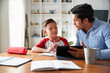 © Monkey Business - Hispanic pre-teen boy sitting at dining room table working with his home school tutor