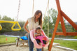© Monkey Business - Young Hispanic mother pushing her baby on a swing at a playground in the park