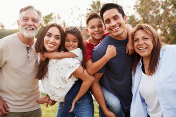 Wall Mural - Three generation Hispanic family standing in the park, smiling to camera, selective focus