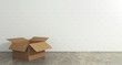 Empty open cardboard box on the floor with a wall background. Concept of moving and shipping