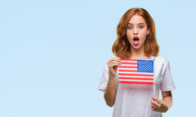 Poster - Young beautiful woman holding flag of america over isolated background scared in shock with a surprise face, afraid and excited with fear expression