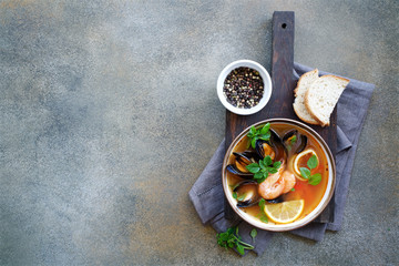 Wall Mural - Fish soup with herbs and tomatoes in bowl. Gray background, top view, empty space for text