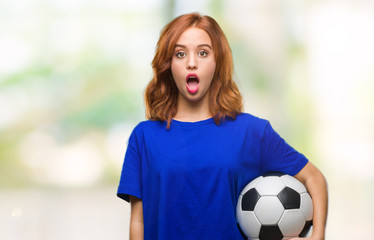 Wall Mural - Young beautiful woman over isolated background holding soccer football ball scared in shock with a surprise face, afraid and excited with fear expression