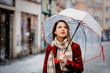 © Masson - Beautiful adult girl in red coat and scarf with umbrella white snowfall stay on city street