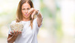 © Krakenimages.com - Middle age hispanic woman eating popcorn over isolated background with angry face, negative sign showing dislike with thumbs down, rejection concept