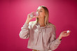 © primipil - Young woman with a bottle of drinking water on a pink background