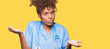 © Krakenimages.com - Young african american doctor woman over isolated background clueless and confused expression with arms and hands raised. Doubt concept.