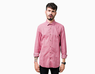 Wall Mural - Young handsome man wearing pink shirt over isolated background In shock face, looking skeptical and sarcastic, surprised with open mouth