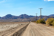 An unpaved road in the Californian desert, with rugged hills in the distance