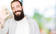 © Krakenimages.com - Young man with long hair, beard and earrings smiling positive doing ok sign with hand and fingers. Successful expression.