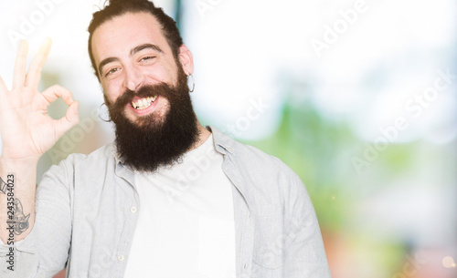 Young Man With Long Hair Beard And Earrings Smiling Positive