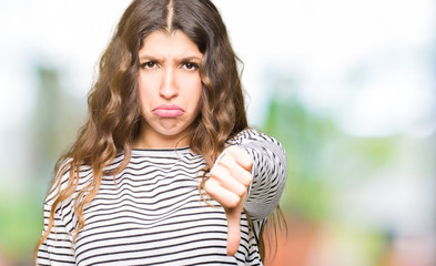 Sticker - Young beautiful woman wearing stripes sweater looking unhappy and angry showing rejection and negative with thumbs down gesture. Bad expression.