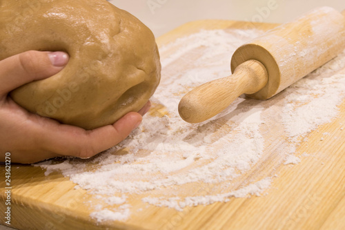 Fotografie, Obraz The girl's hands with a dough and rolling pin on a wooden table