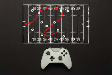 Wall Mural - White gamepad on a black background. Added a soccer field scheme. Tactics of the game. Concept game of American football on the console, computer games. Flat lay, top view.