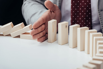 close up view of businessman preventing wooden blocks from falling with copy space