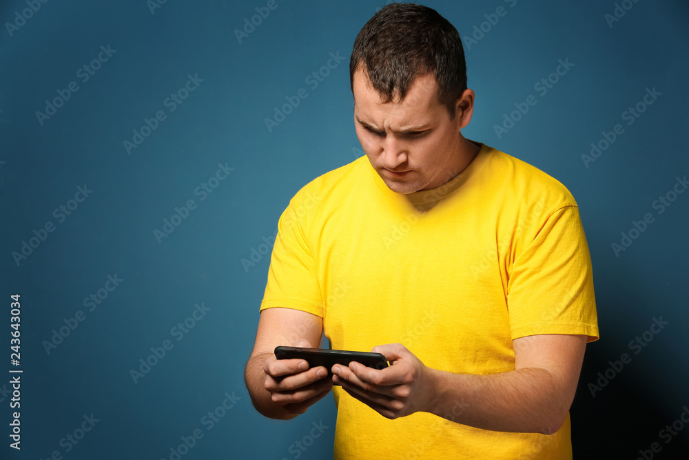 Young man playing game on smartphone against color background