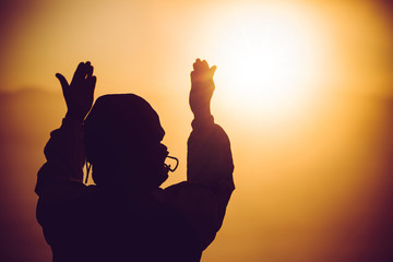 Canvas Print - Silhouette of man praying at the top mountain with abstract sun cross ray god power