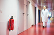 Krankenhaus mit Korridor Feuerlöscher und Frau unscharf in Zentralperspektive