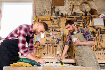 Wall Mural - profession, carpentry, woodwork and people concept - two carpenters working and drinking coffee at workshop