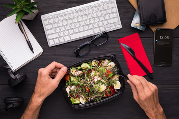 Businessman enjoying healthy salad at work desk