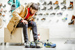 © rh2010 - Man in winter jacket trying shoes for mountain hiking sitting in the fitting room of the modern sports shop