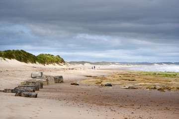 Poster - DRURIDGE BAY, ENGLAND, UK - JUNE 03, 2016: People walking along the golden sands of Druridge Bay in Northumberland, England.