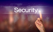 A hand selecting a Security business concept on a clear screen with a colorful blurred background.