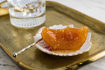 Wall Mural - Home-made orange spoon sweet and glass of cold water on vintage bronze tray.