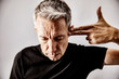 © Westend61 - Portrait of mature man making shooting gesture with his hand against his temple