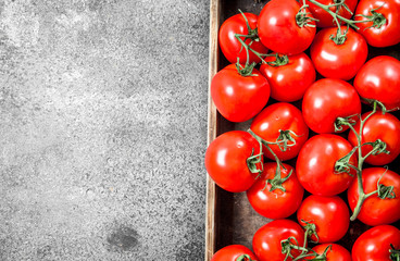 Ripe tomatoes on a wooden tray.