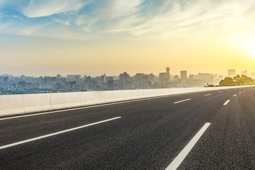 Panoramic city skyline and buildings with empty asphalt road at sunrise