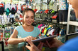 © DragonImages - Female sports store customer entering payment details into app on tablet computer in hands of cashier