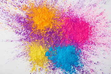 top view of explosion of multicolored holi powder on white background