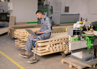 Wall Mural - Disabled young man with an artificial leg is working at the furniture  factory