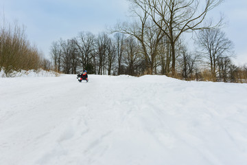 children on two sledges descend from the hills