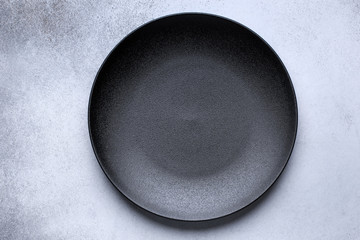 empty black plate on gray concrete background. top view, with copy space