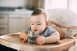 A child on a high chair drinking water from a glass