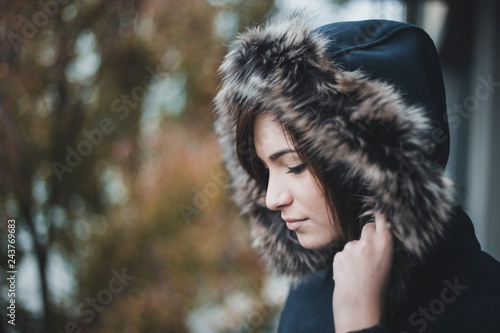 Fotografía Close up autumn portrait of young and cute woman in blue jacket with furry hood on her head