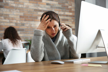 Wall Mural - Stressed technical support operator working at table in office