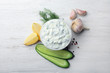 Tzatziki cucumber sauce with ingredients on wooden background, flat lay