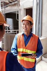 Cheerful mature Vietnamse contractor meeting new worker at construction site