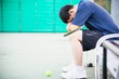 Sad tennis player sitting in the court after lose a match - people in sport tennis game concept