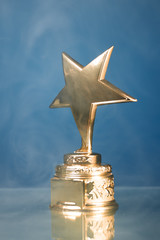 Wall Mural - gold star trophy in smoke, blue background