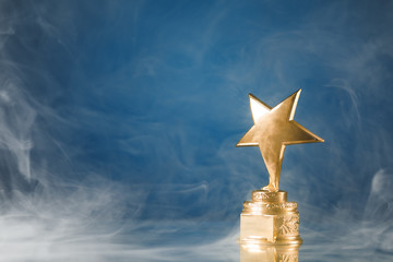 Wall Mural - gold star trophy in smoke, blue background