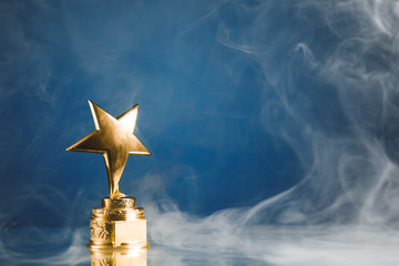 Wall Mural - gold star trophy in smoke, blue background