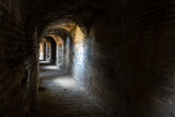 Fototapeta Desenie - Curved stone tunnel with sun light beams