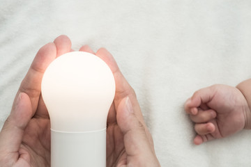 Poster - Light bulb in mother hand and baby hand: concept of idea for kid