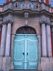 Light green ornate vintage wooden double entry door with decorative carving and stone columns